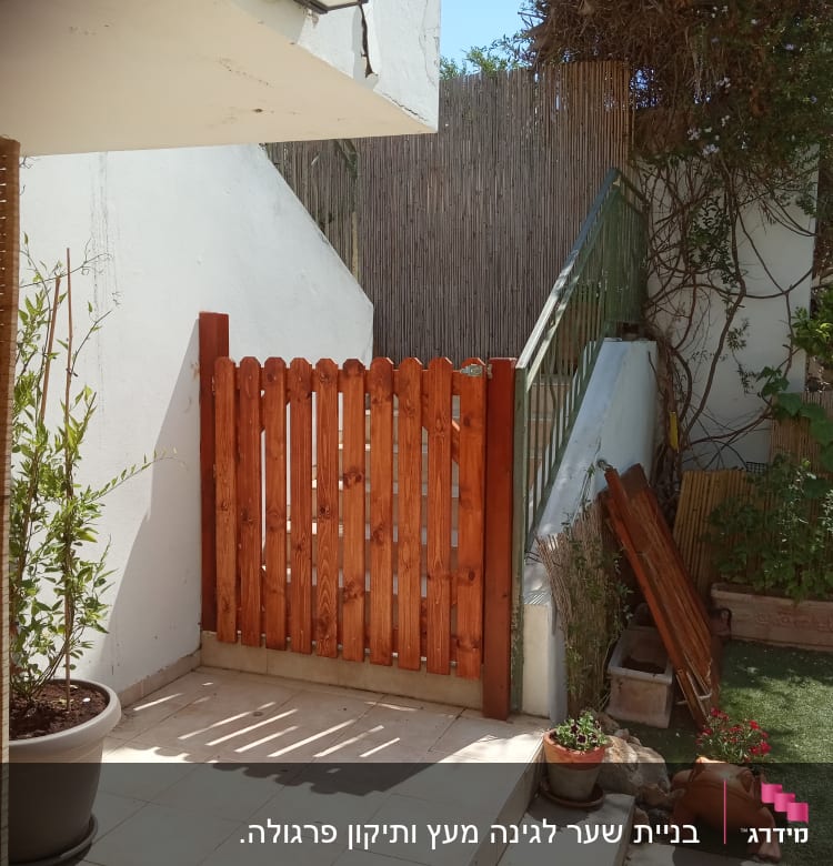 שער עץ בגינה עם צמחים ועציצים